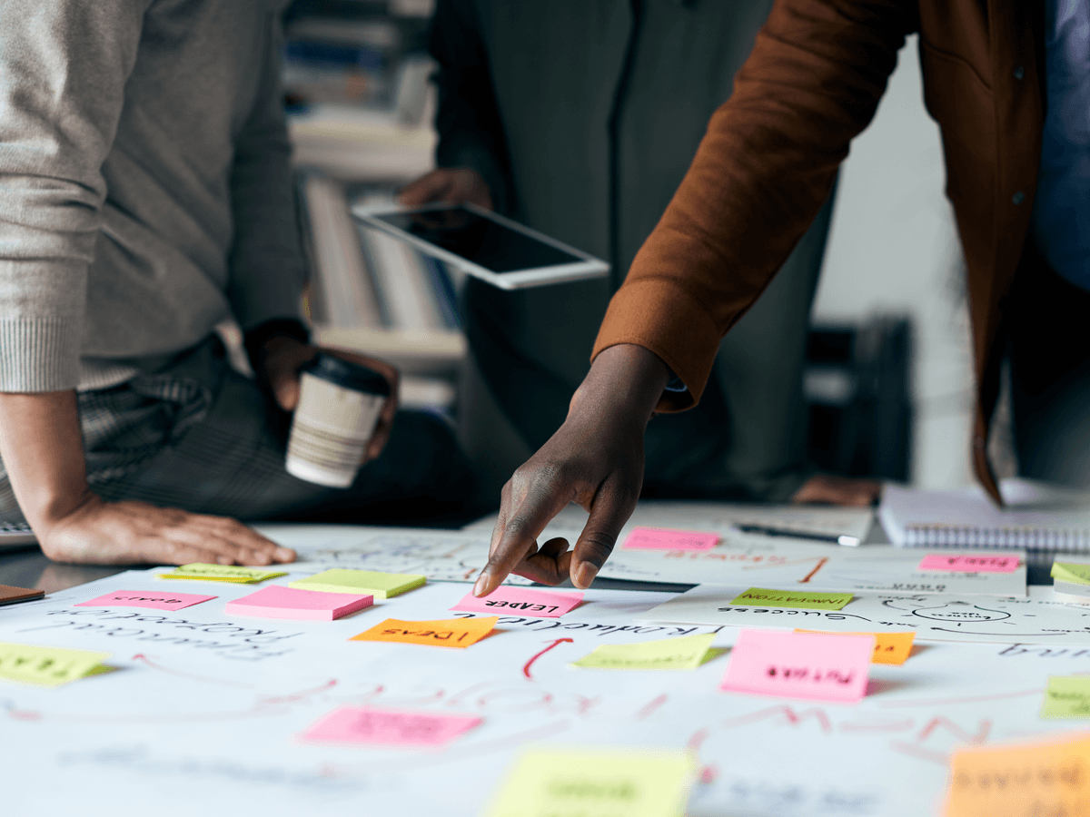 Hands pointing at sticky notes on a table